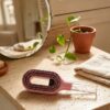 Brosse Cascadhe en ambiance salle de bain travertin avec plante pothos