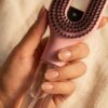 Main feminine tenant la brosse Cascadhe, gros plan sur le reservoir transparent