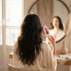 Cascadhe en routine matinale devant miroir vintage, peignoir soie creme